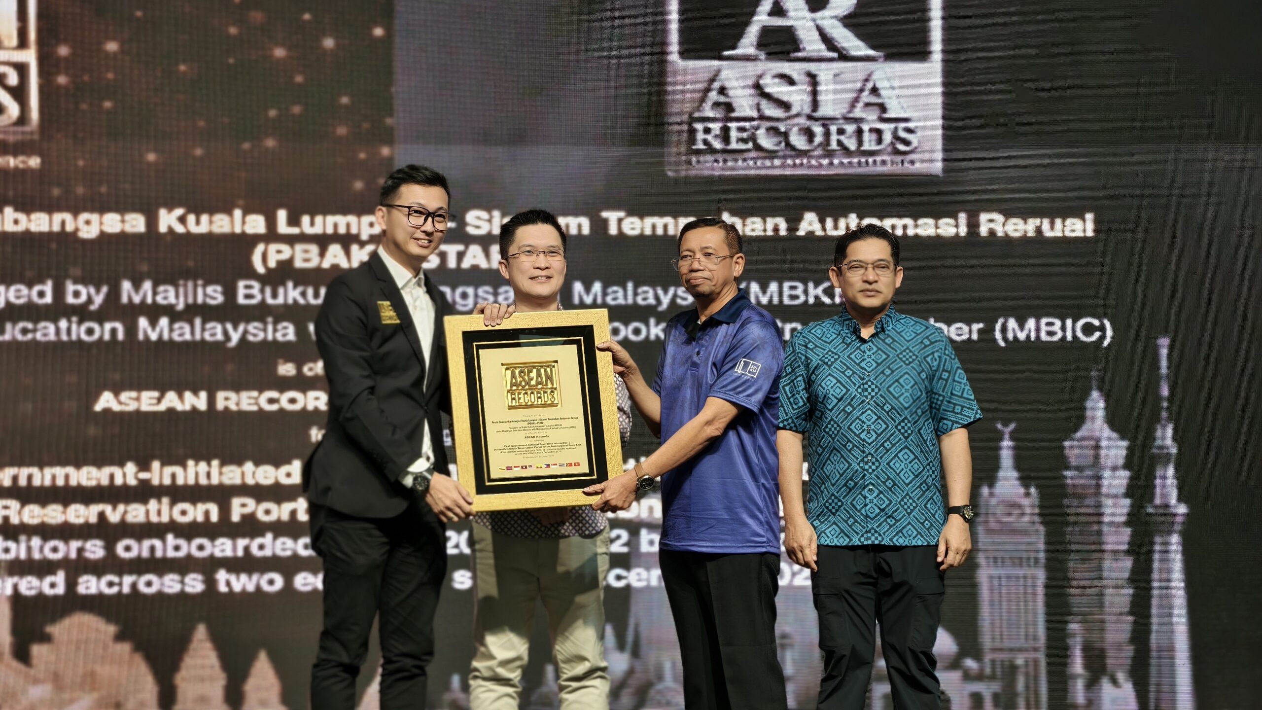 Four men on stage exchange a framed award plaque at an ASEAN Records ceremony, backdrop displays logos and text.
