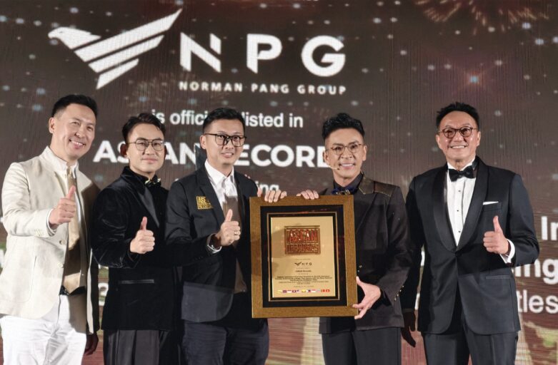 Six men in formal attire pose on a stage, holding a framed award plaque with an NPG backdrop behind them, showing a celebratory moment.