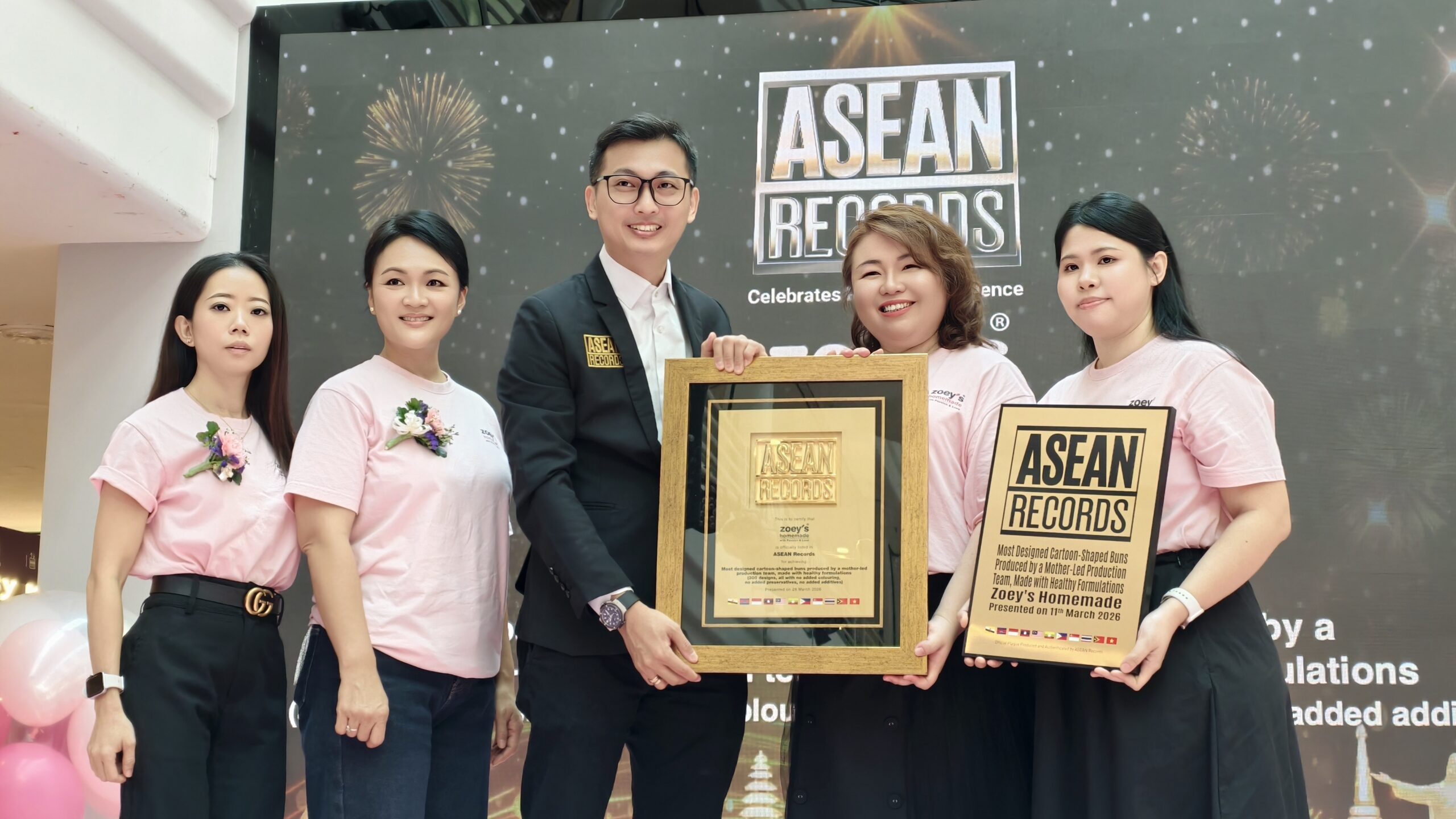 Group of five people posing with awards at a ceremony, man in suit center holding a framed plaque with 'ASEAN RECORDS' logo behind them.