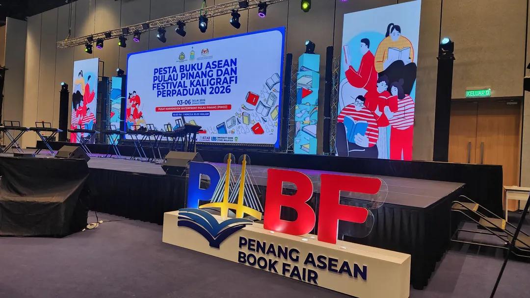 Stage setup for the Penang ASEAN Book Fair with oversized PBF letters and a reading-themed backdrop on large screens and banners.